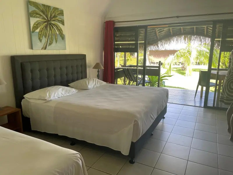 Une chambre lumineuse avec un grand lit blanc et un accès à une terrasse.