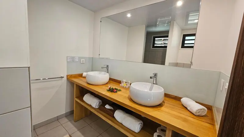 Une salle de bain lumineuse avec deux vasques sur un meuble en bois.