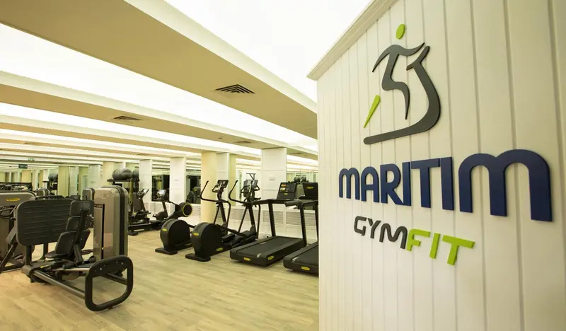 Une salle de sport lumineuse avec des équipements de musculation et de cardio.