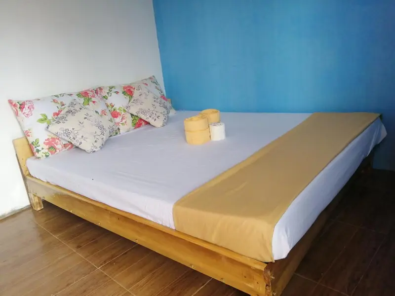 Un lit recouvert d'une courtepointe fleurie et d'un drap jaune dans une pièce lumineuse.