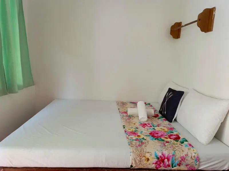 Une chambre lumineuse avec un lit recouvert d'une courtepointe fleurie.