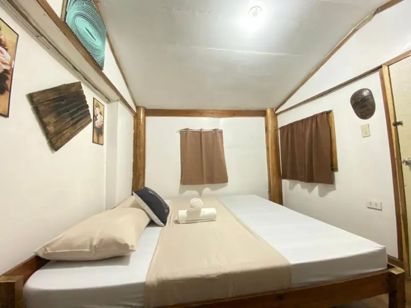 Une chambre simple avec un lit fait et des rideaux aux fenêtres.