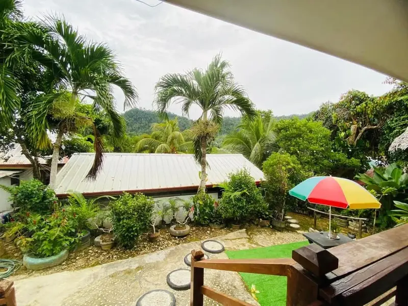 Vue sur une végétation luxuriante et des bâtiments depuis une terrasse.