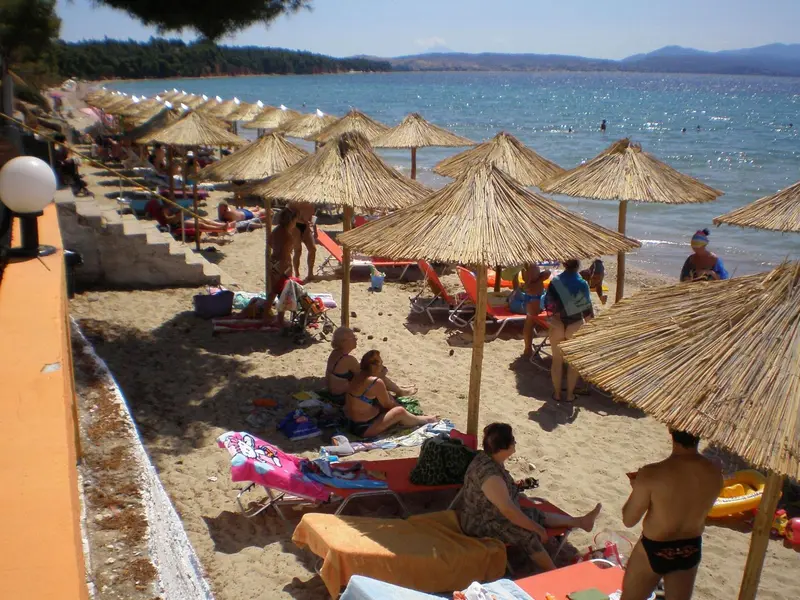 Plage ensoleillée avec parasols en chaume et transats.