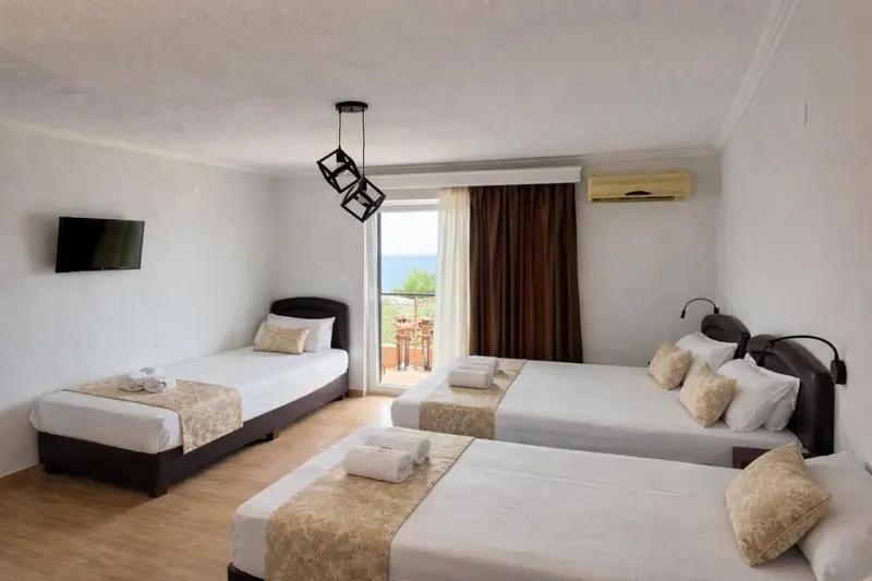Chambre lumineuse avec deux lits simples et un grand lit double, vue sur la mer.