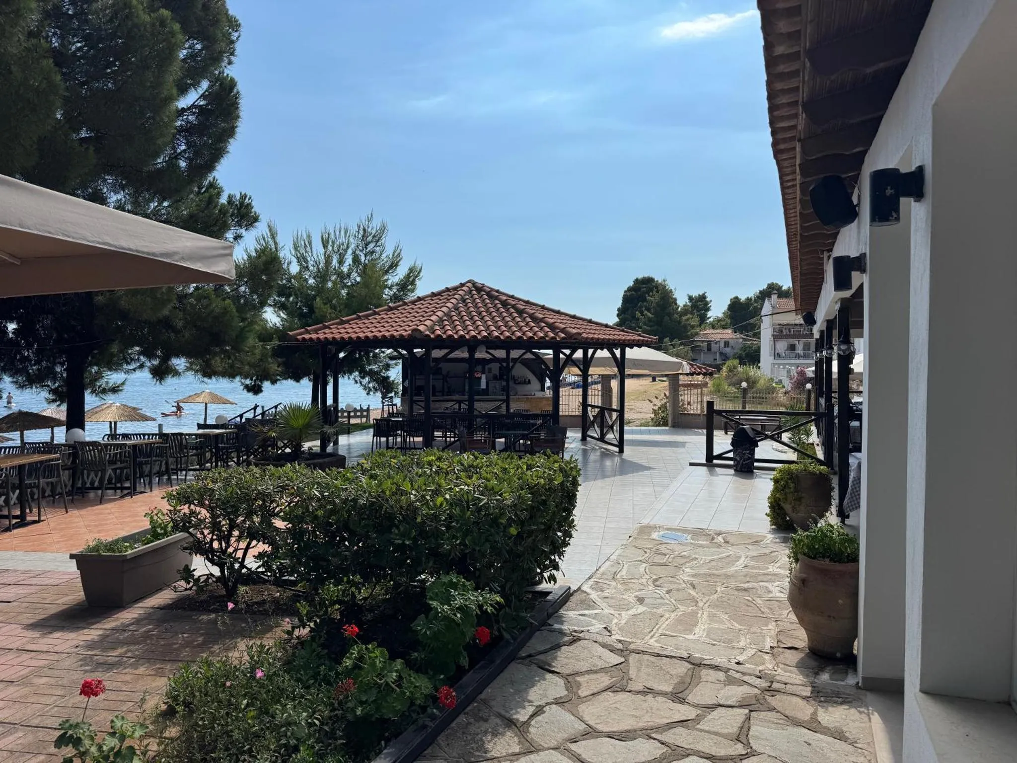 Terrasse ombragée avec mobilier de jardin et vue sur la mer.
