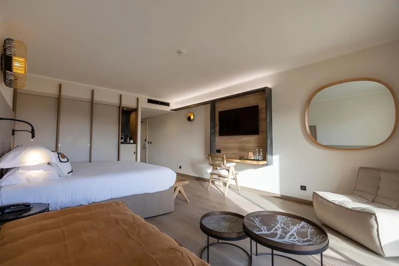 Une chambre lumineuse avec un grand lit et un coin salon.