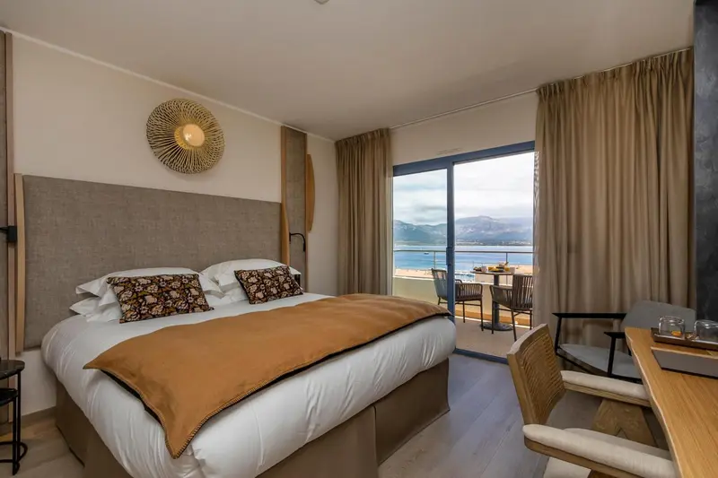 Une chambre lumineuse avec un grand lit donnant sur une vue mer.