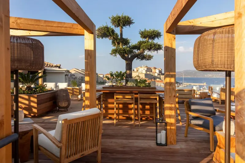 Terrasse aménagée avec mobilier en bois et vue sur la mer.
