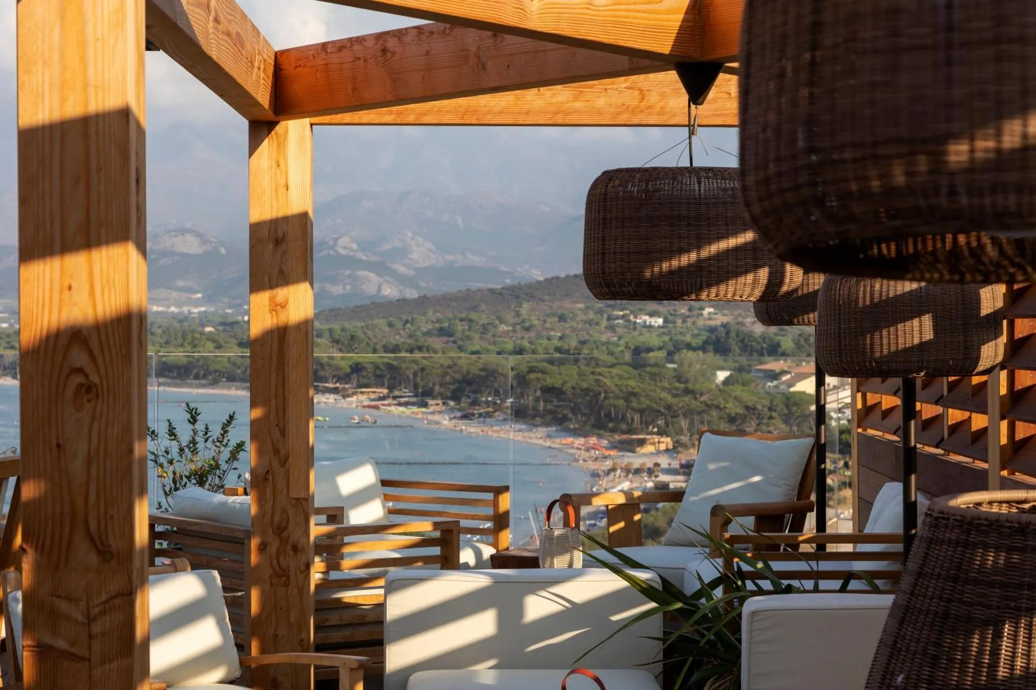 Terrasse ombragée avec vue sur la mer et les montagnes.