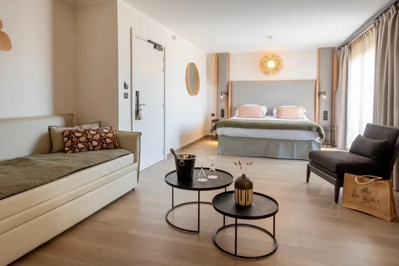 Une chambre lumineuse avec un canapé, des fauteuils et un grand lit.