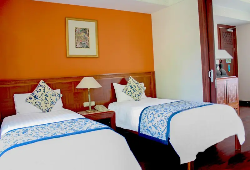 Une chambre lumineuse avec deux lits simples et une décoration murale.
