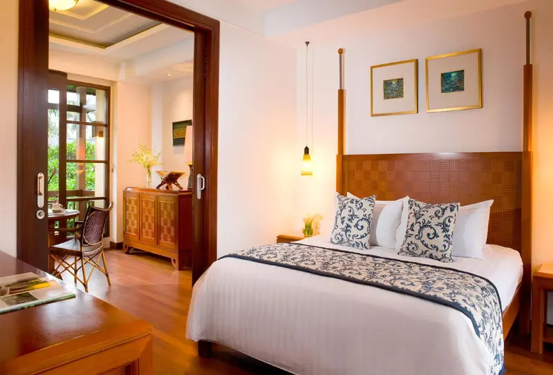 Une chambre lumineuse avec un grand lit et un coin repas attenant.