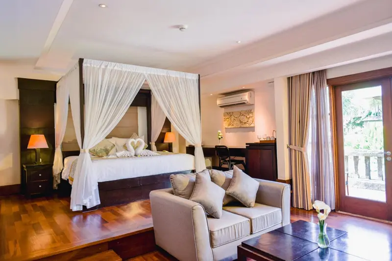 Une chambre spacieuse avec un lit à baldaquin et un coin salon.