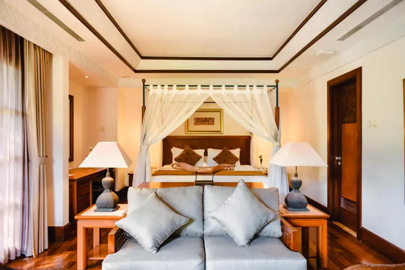 Une chambre lumineuse avec un grand lit à baldaquin et un coin salon.