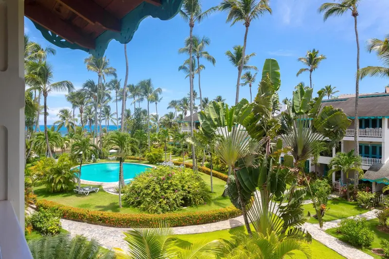 Vue sur une piscine et une végétation luxuriante depuis un balcon.
