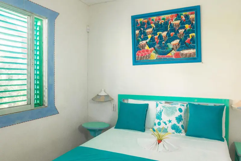 Une chambre lumineuse avec un lit turquoise et une décoration colorée.