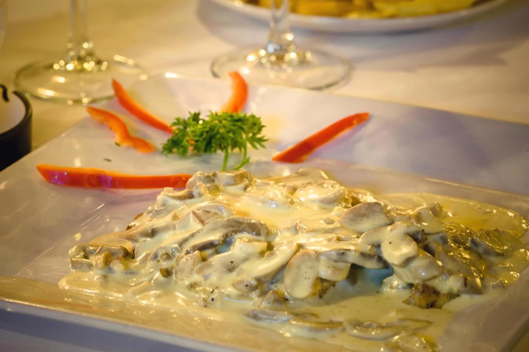 Assiette de champignons à la crème décorée de poivrons et de persil.