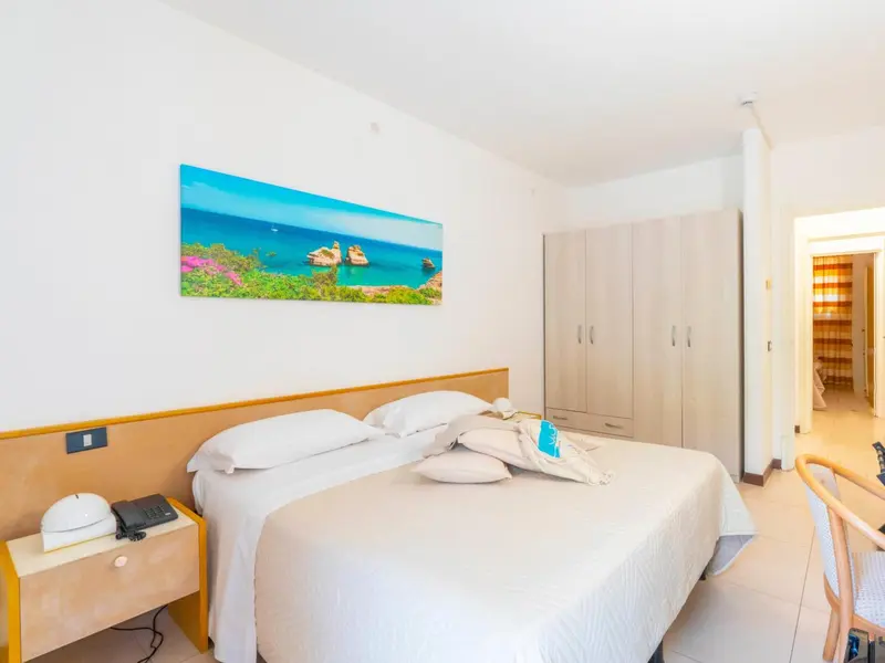 Une chambre lumineuse avec un grand lit et une décoration murale représentant une plage.