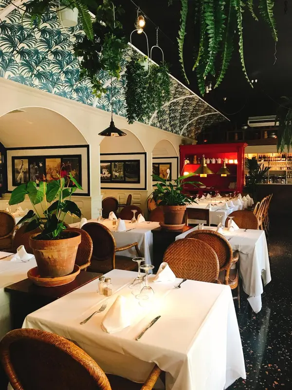Une salle de restaurant lumineuse avec des tables dressées et une décoration florale.