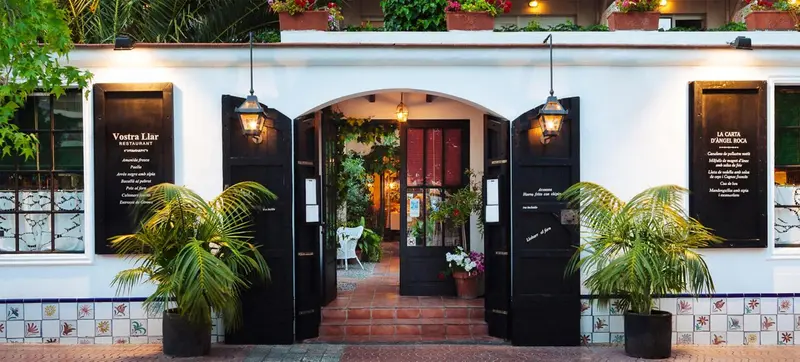 Entree d'un restaurant avec une arche et des plantes vertes.