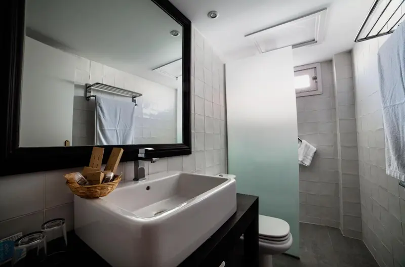 Une salle de bain claire avec lavabo, miroir et douche.