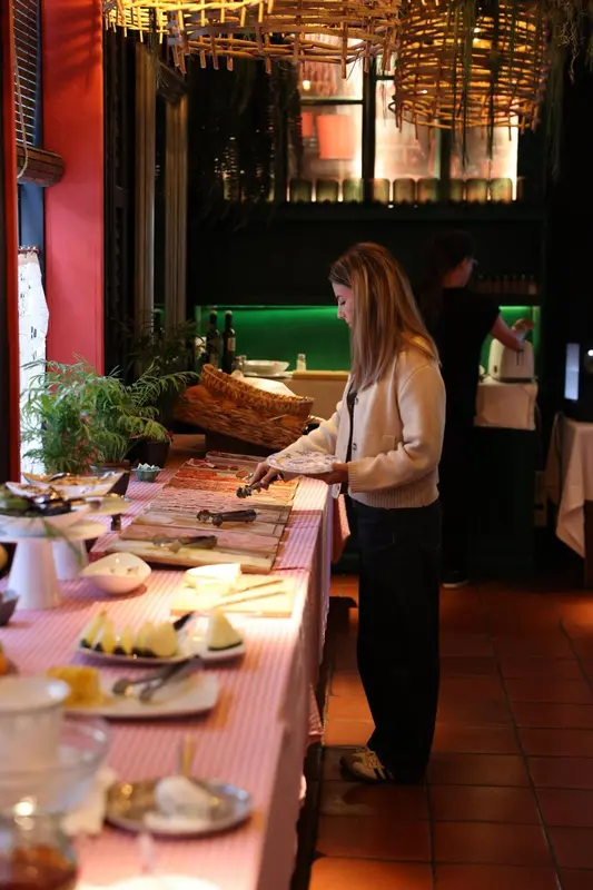 Une personne prépare une table de buffet garnie de fruits et de pâtisseries.