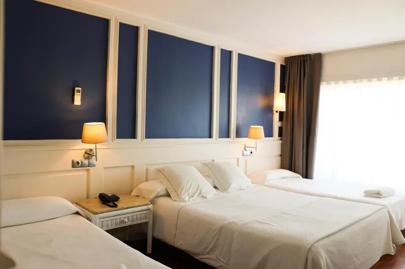 Une chambre lumineuse avec deux lits simples et un mur bleu décoratif.