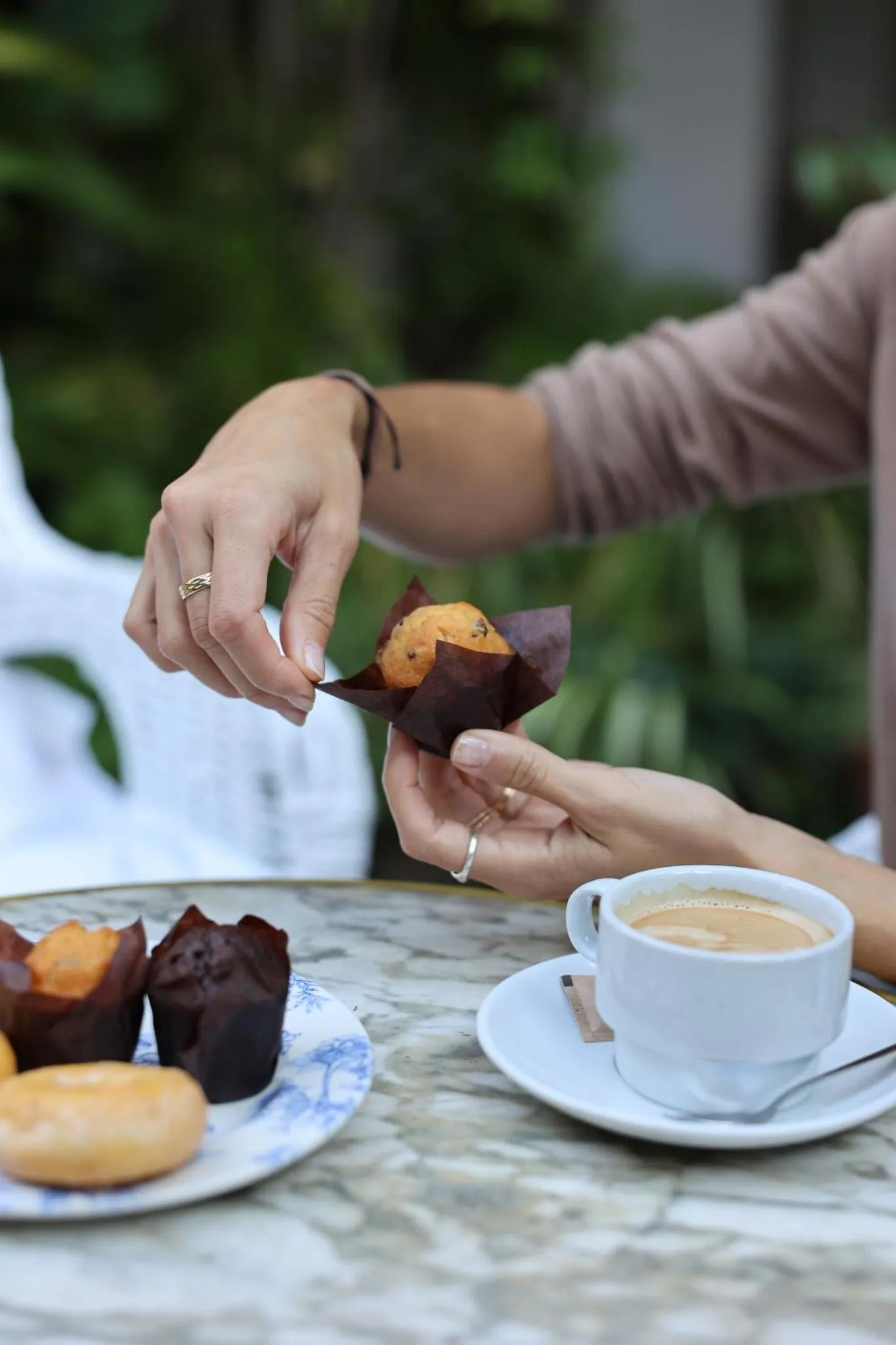 Une personne déguste une pâtisserie et une boisson chaude à une table.