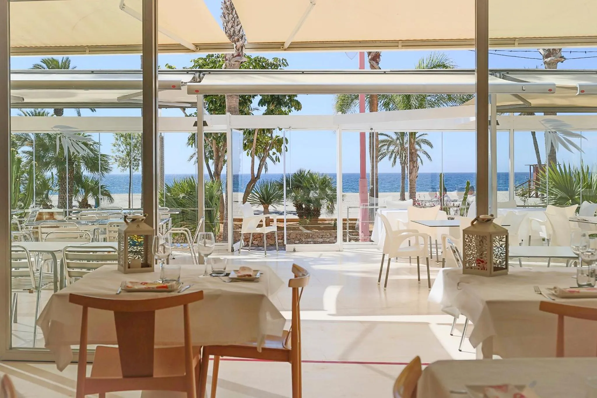 Une salle lumineuse s'ouvre sur une vue de plage et de mer.