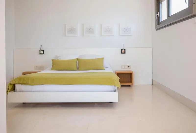 Une chambre lumineuse avec un grand lit recouvert d'une couette verte.