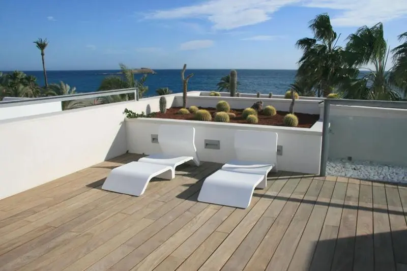 Terrasse aménagée avec mobilier blanc et végétation.