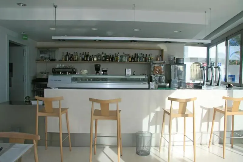 Un comptoir de bar moderne avec des tabourets et des bouteilles exposées.