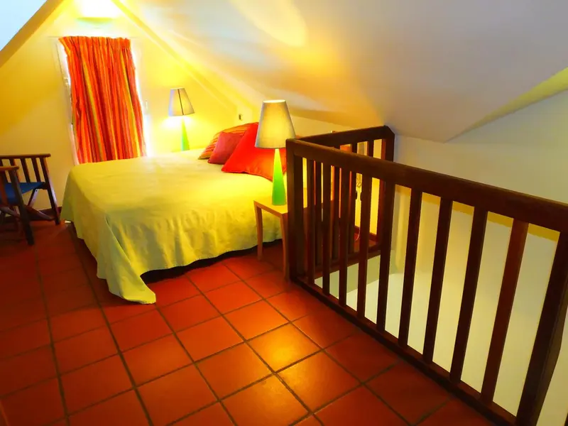 Une chambre mansardée lumineuse avec un lit recouvert d'une couverture verte.