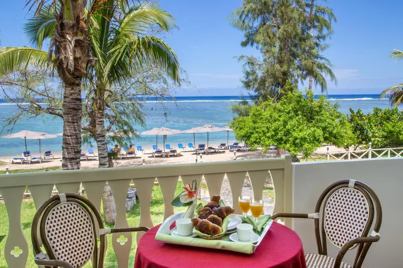 Une table avec un petit-déjeuner est placée sur une terrasse avec vue sur la mer et la plage.