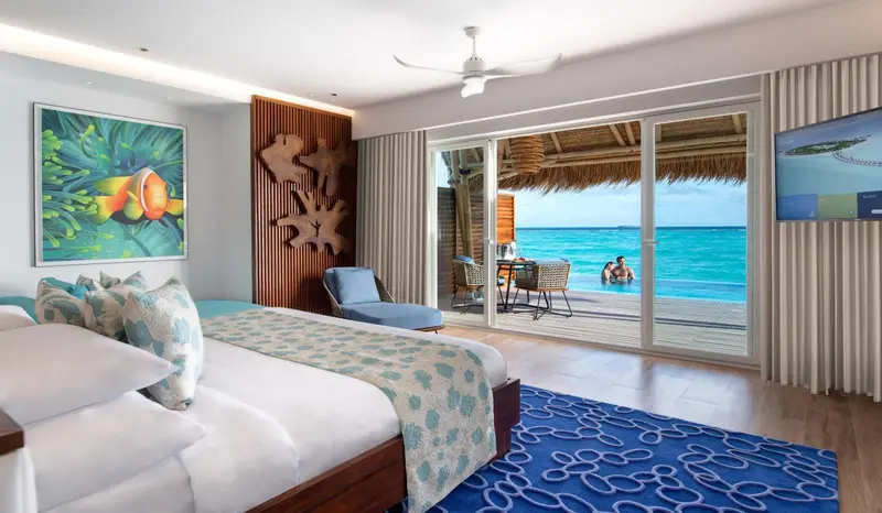 Une chambre lumineuse s'ouvre sur une terrasse avec vue sur la mer turquoise.