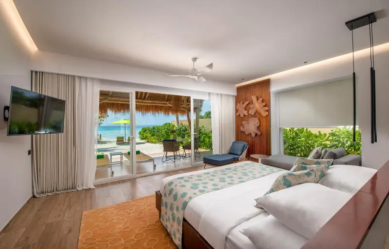 Chambre lumineuse avec un grand lit et vue sur la mer.