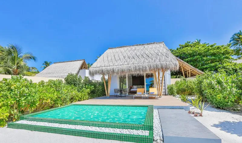 Une terrasse privée avec piscine donne sur un bungalow de style tropical.