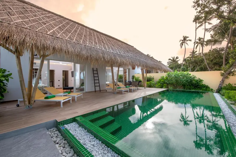 Terrasse avec chaises longues donnant sur une piscine turquoise.