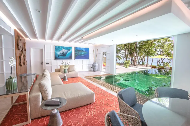 Un salon lumineux s'ouvre sur une piscine et une végétation luxuriante.