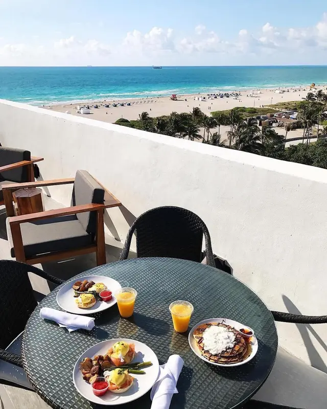Une table est dressée avec des assiettes et des boissons sur une terrasse ensoleillée.