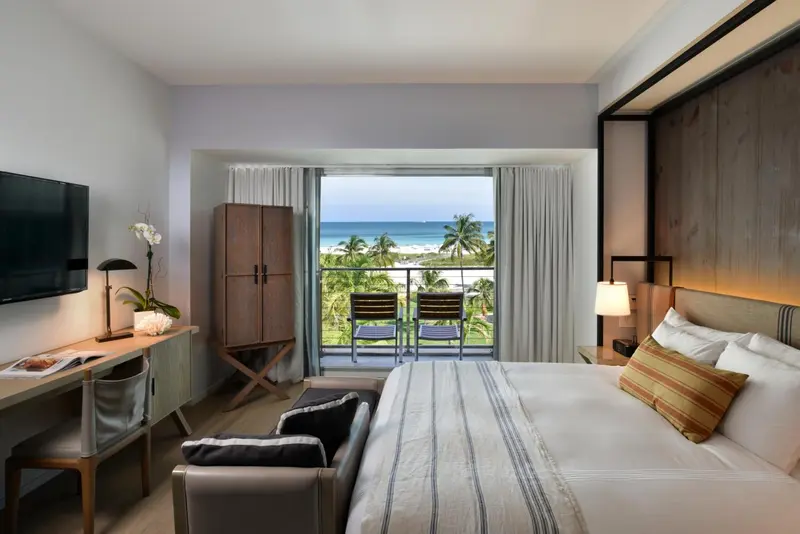Une chambre lumineuse avec un grand lit et un balcon donnant sur la mer.