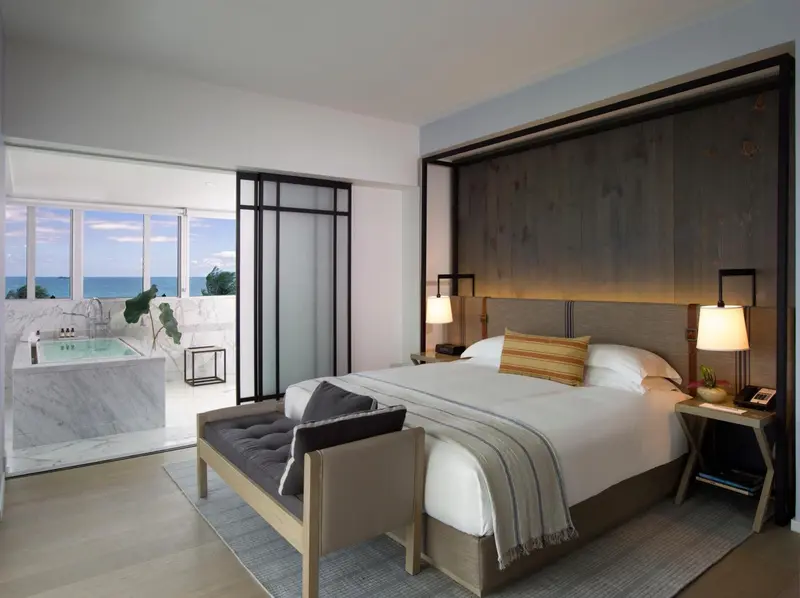 Une chambre moderne avec un grand lit et un bain à remous sur une terrasse.