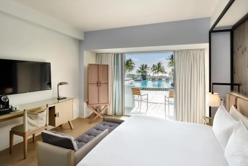 Une chambre lumineuse avec un lit et un accès à une terrasse avec vue sur la piscine.