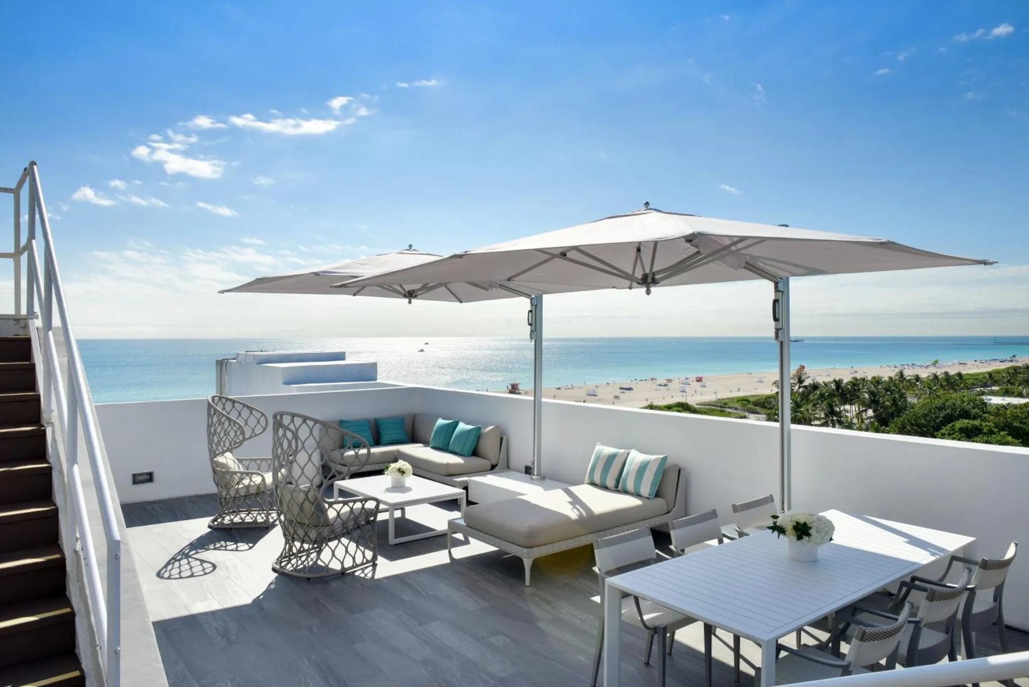 Terrasse aménagée avec salon et table à manger offrant une vue sur la mer.