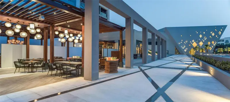 Terrasse ombragée avec tables et canapés confortables.