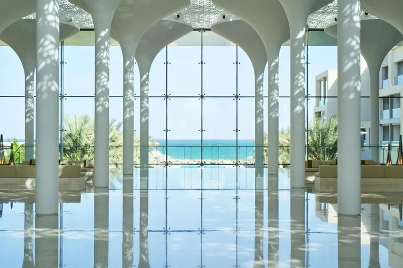 Vaste espace intérieur lumineux donnant sur la mer à travers de grandes baies vitrées.