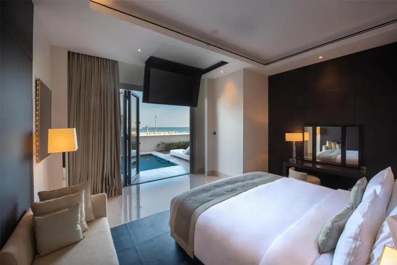 Une chambre lumineuse s'ouvre sur une terrasse avec piscine et vue sur la mer.