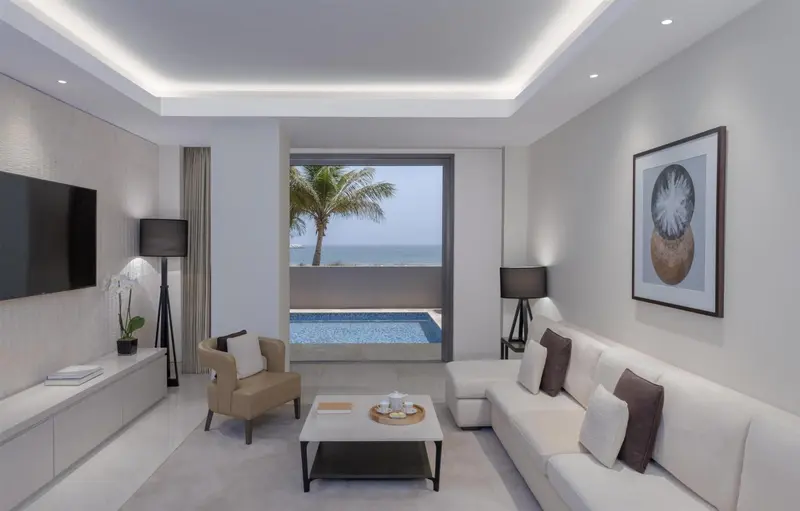 Un salon lumineux s'ouvre sur une terrasse avec piscine et vue sur la mer.