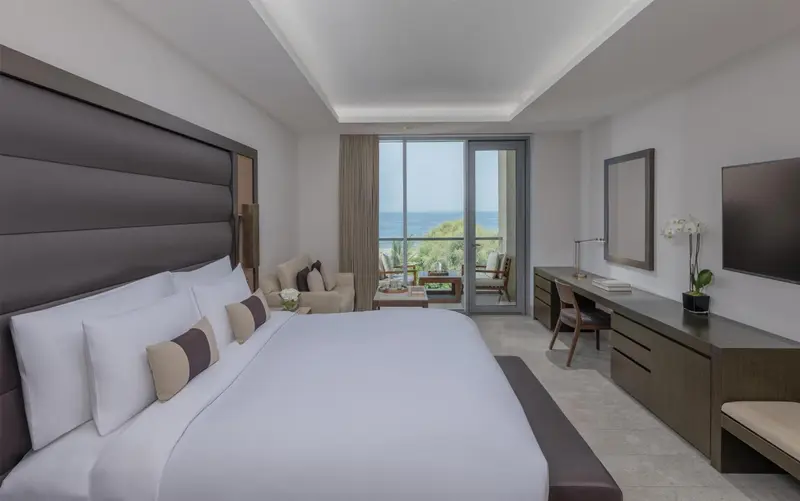 Chambre lumineuse avec un grand lit et une vue sur la mer.